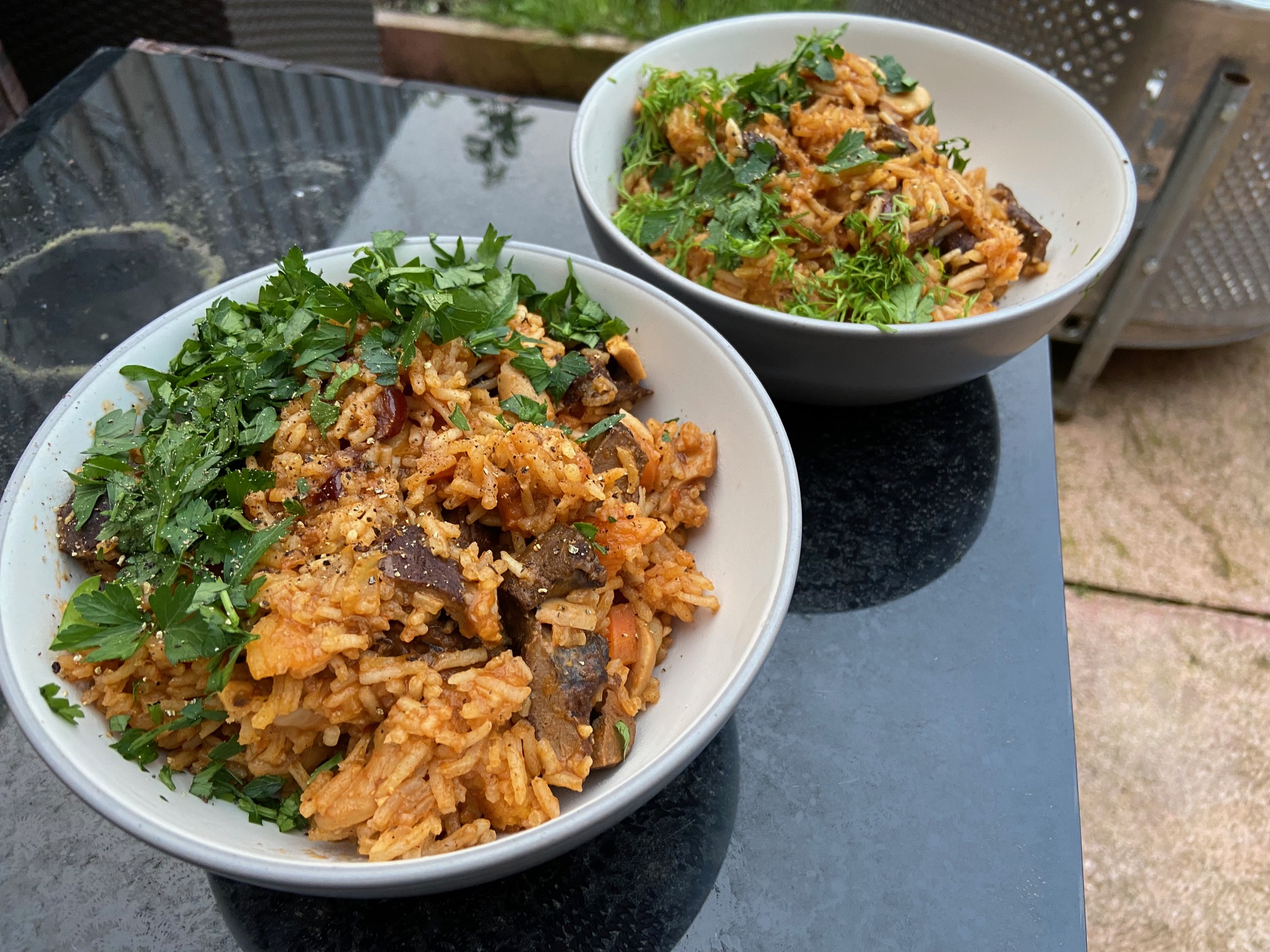 2 bowls of plov on a dirty garden table